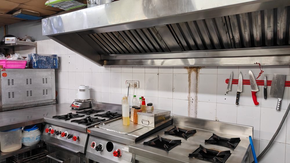 Commercial gas range under a chimney hood in a Blue Wings cloud kitchen, Chandigarh